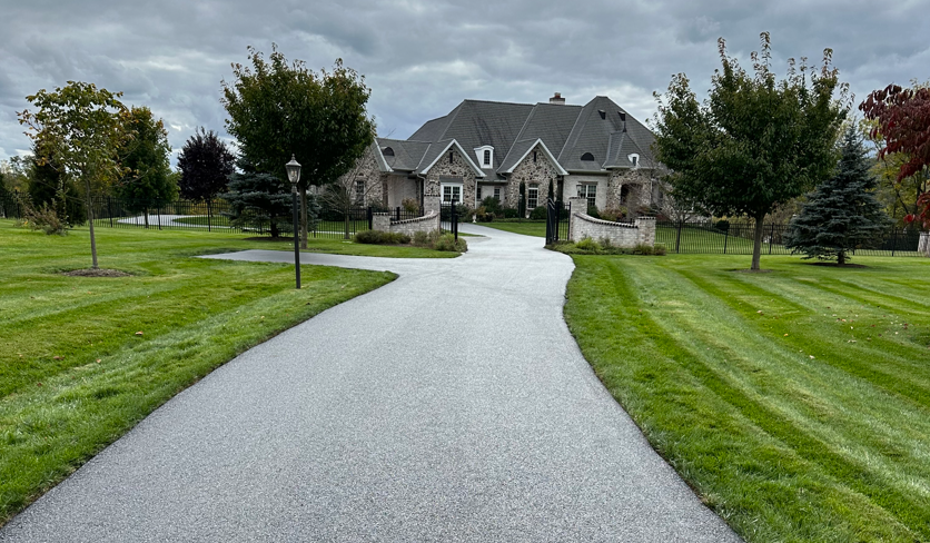 Long, paved driveway lane for a large, gated house.