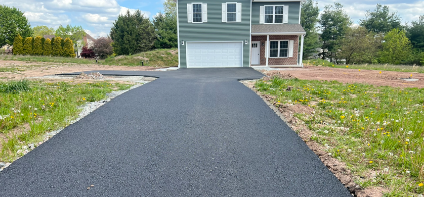 Newly, installed asphalt driveway leading to a new construction house.