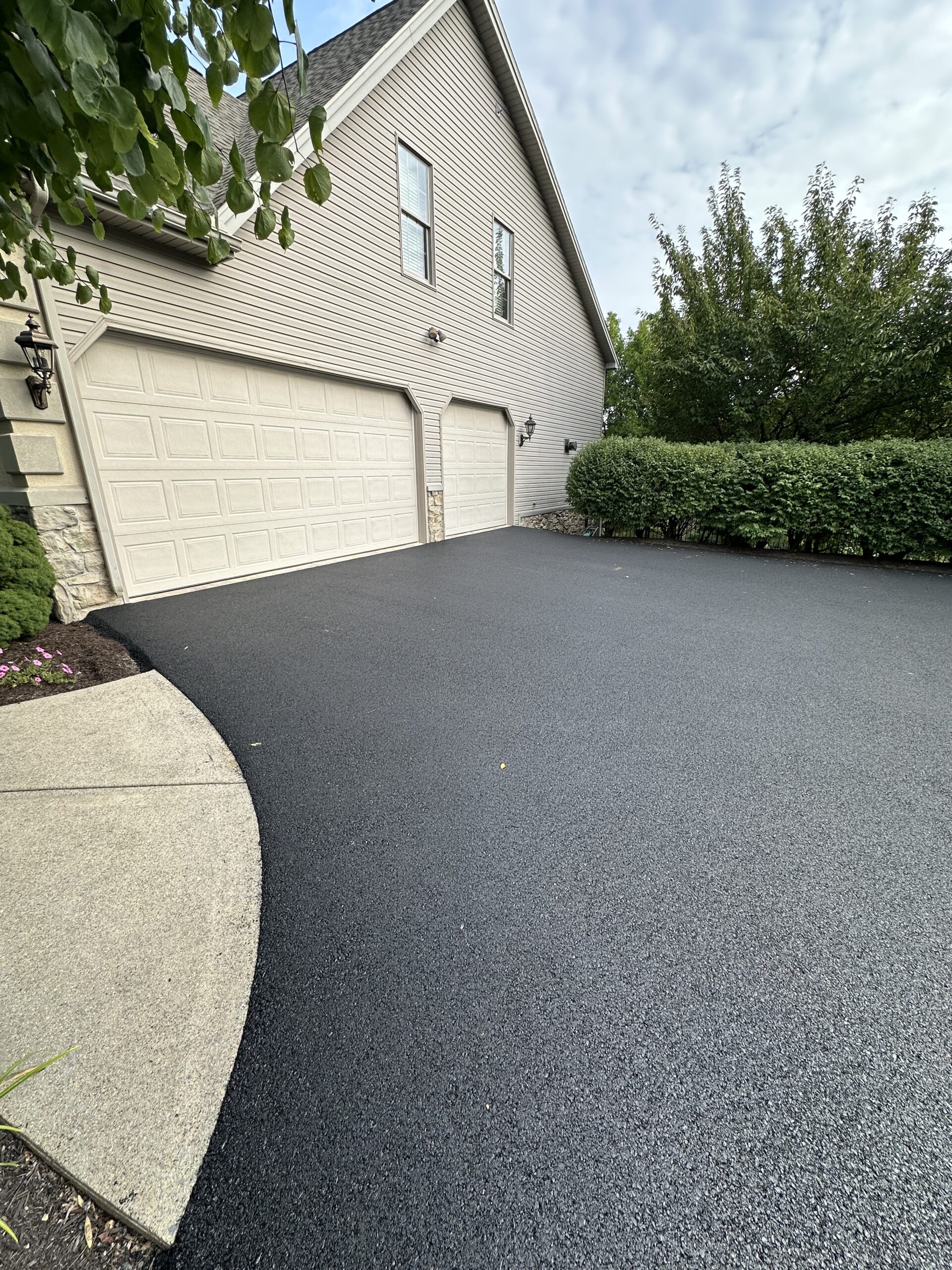 Newly paved entrance to garage. The asphalt driveway and the cement garage apron are completely flush.