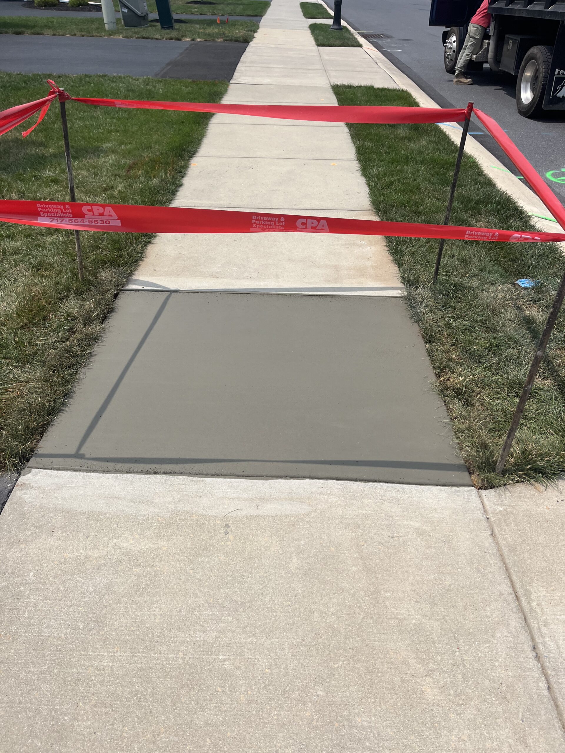 Poured concrete sidewalk section with caution tape around it.