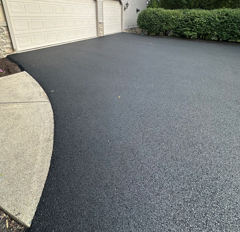 Newly paved entrance to garage. The asphalt driveway and the cement garage apron are completely flush.