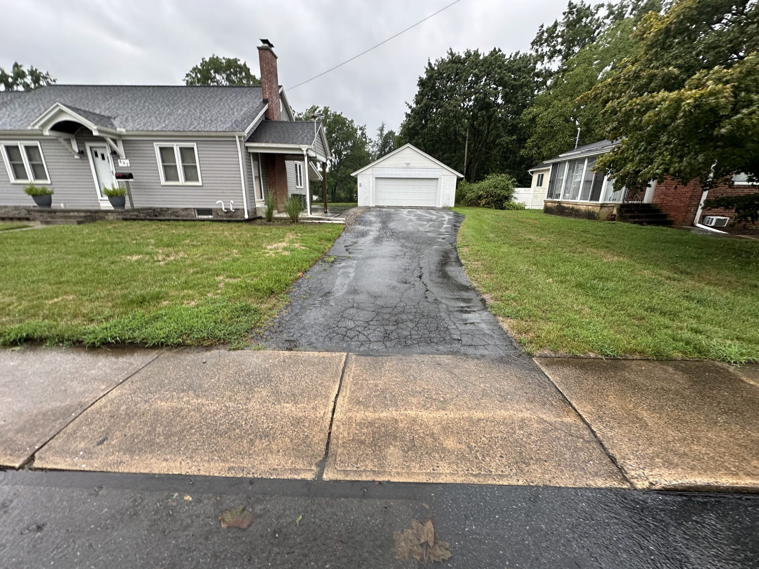 Broken, cracked driveway leading to a white, detached garage.