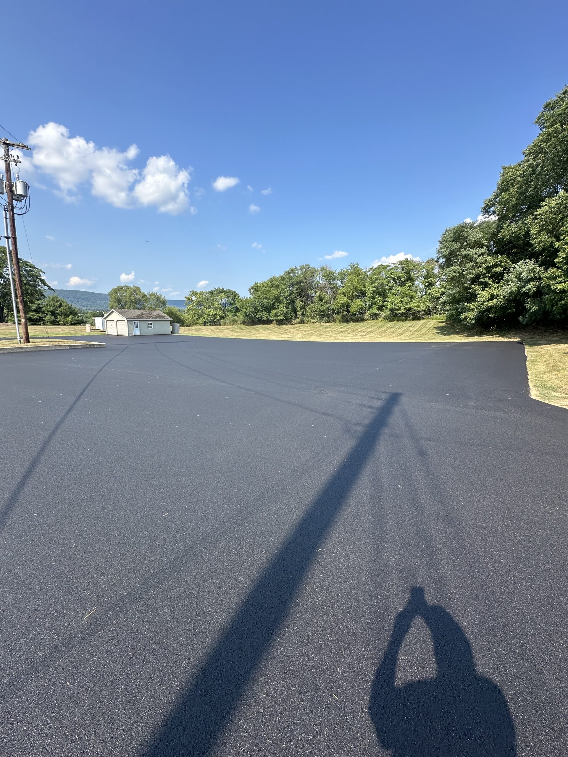 Paved large parking area with trees in the background.