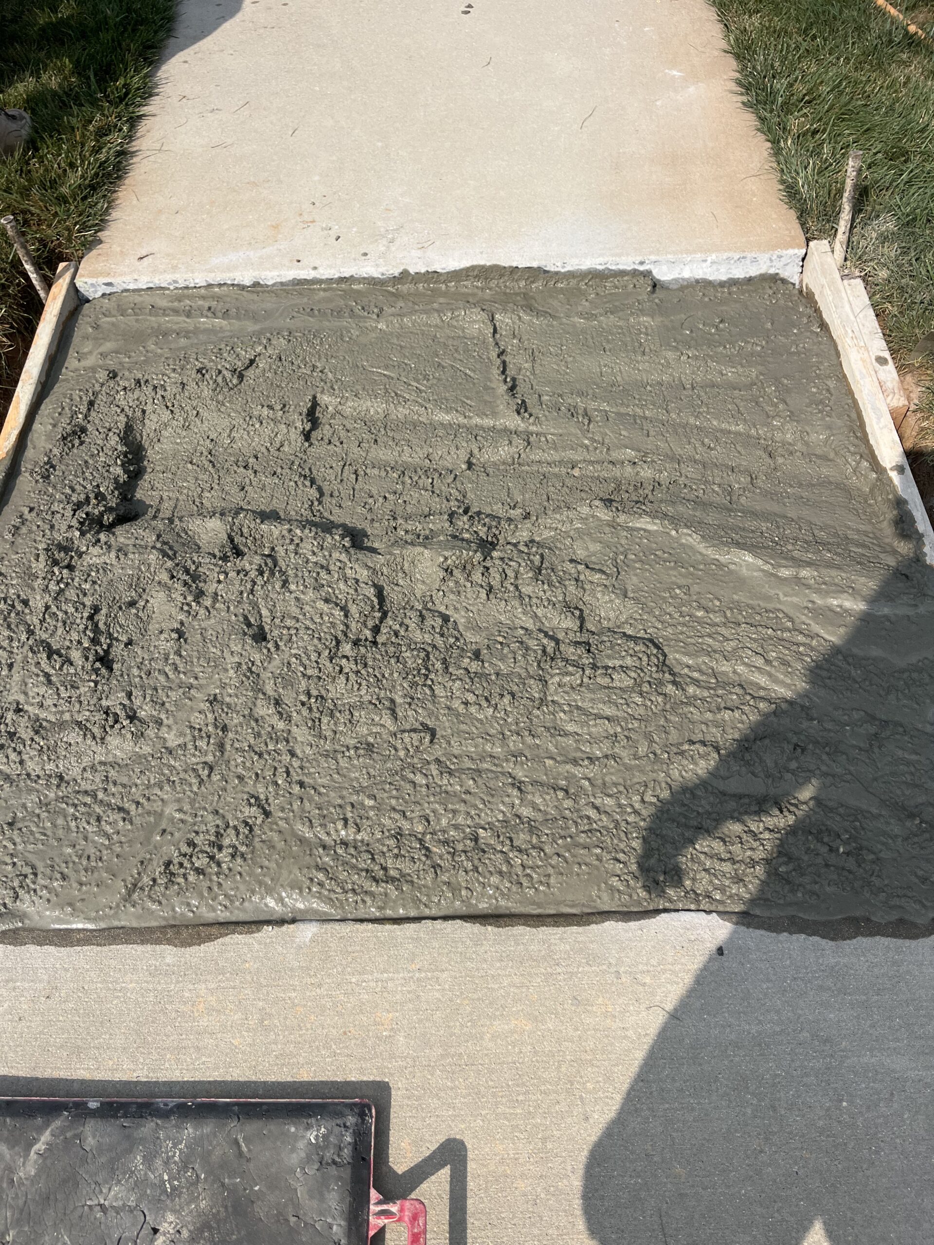 A freshly poured section of concrete sidewalk. It has not been troweled or brushed yet.